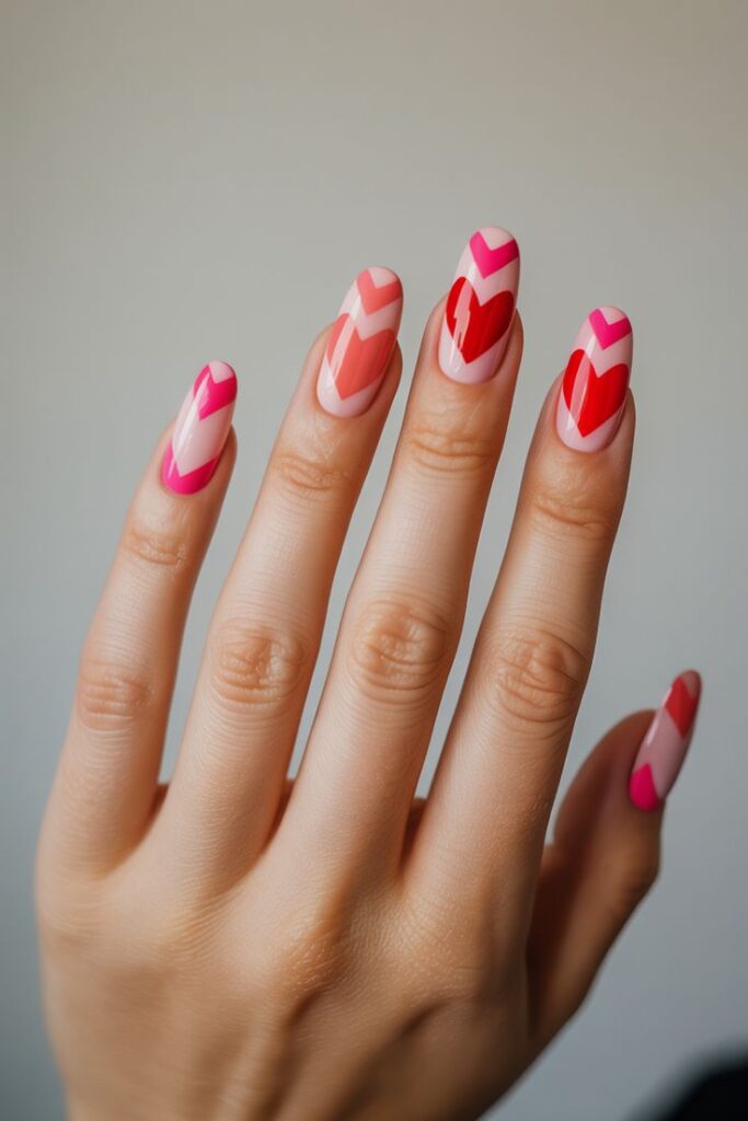 Nails with a nude base, orange, red hearts, alternated with negative space heart in pink