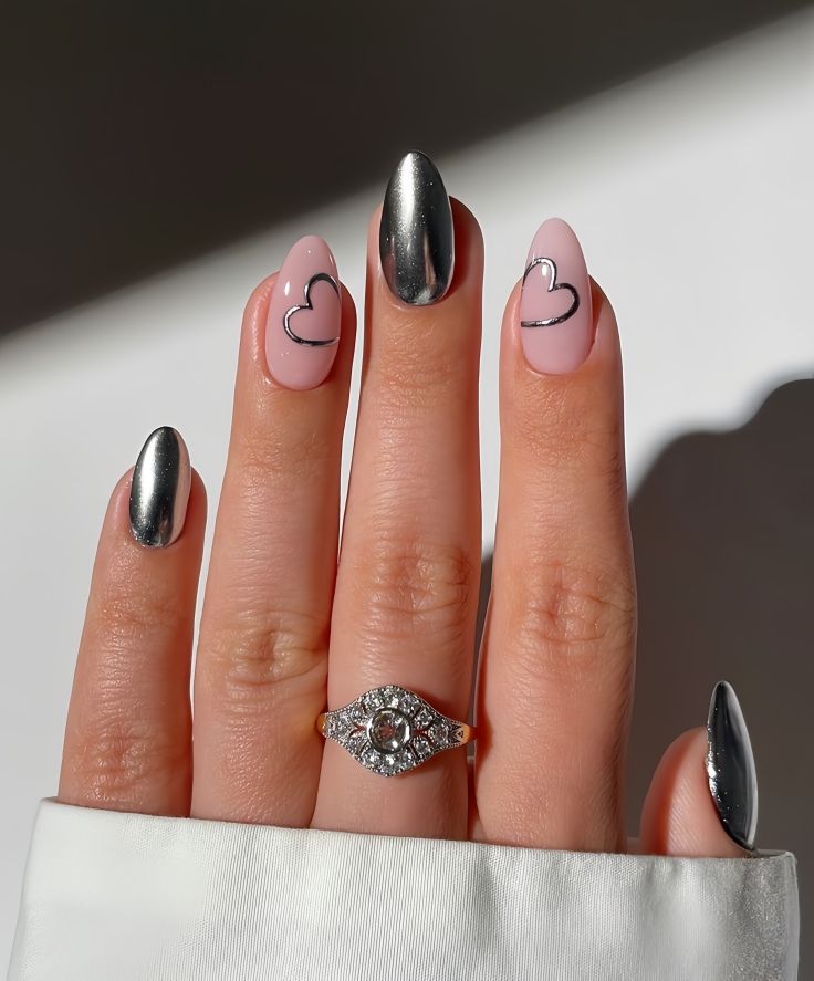 nails with pinky, middle finger and thumb in silver chrome. Outline of hearts tilting towards the center in the same silver chrome is painted on the remaining fingers.