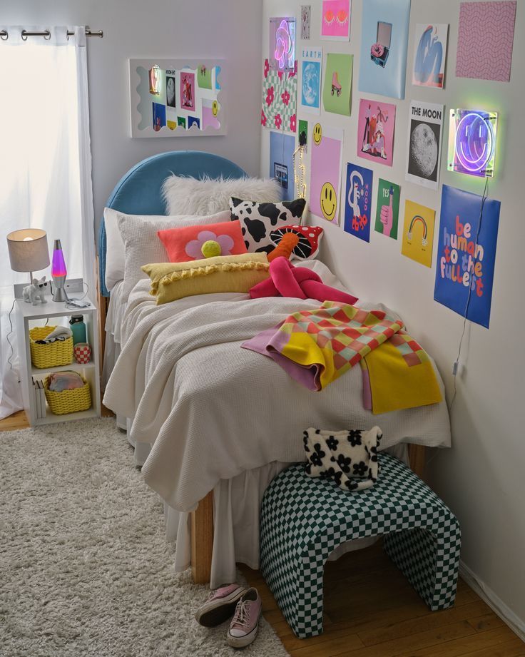 vibrant, maximalist dorm room featuring a bed blue cureved headboard surrounded by walls covered in bright posters and neon signs