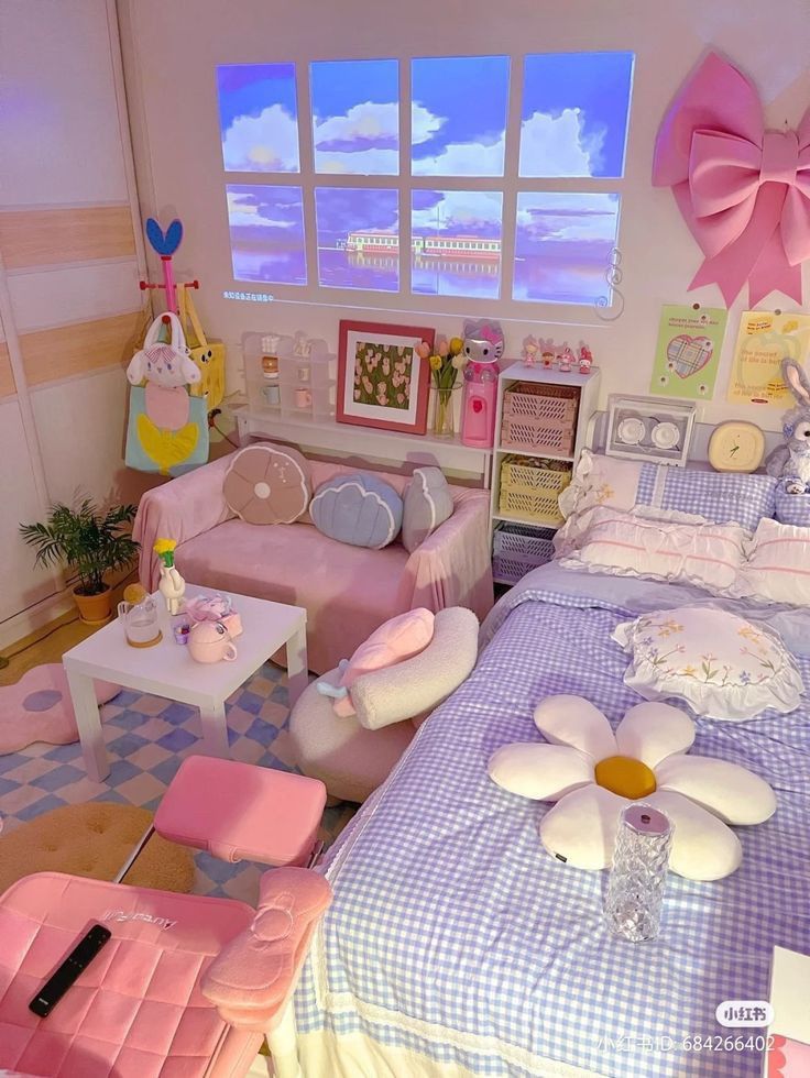 A dreamy pastel bedroom featuring a blue and white checkered duvet, a large pink decorative wall bow, flower-shaped accent pillows, and a light pink mini-couch and desk chair over a blue and cream checkered floor.