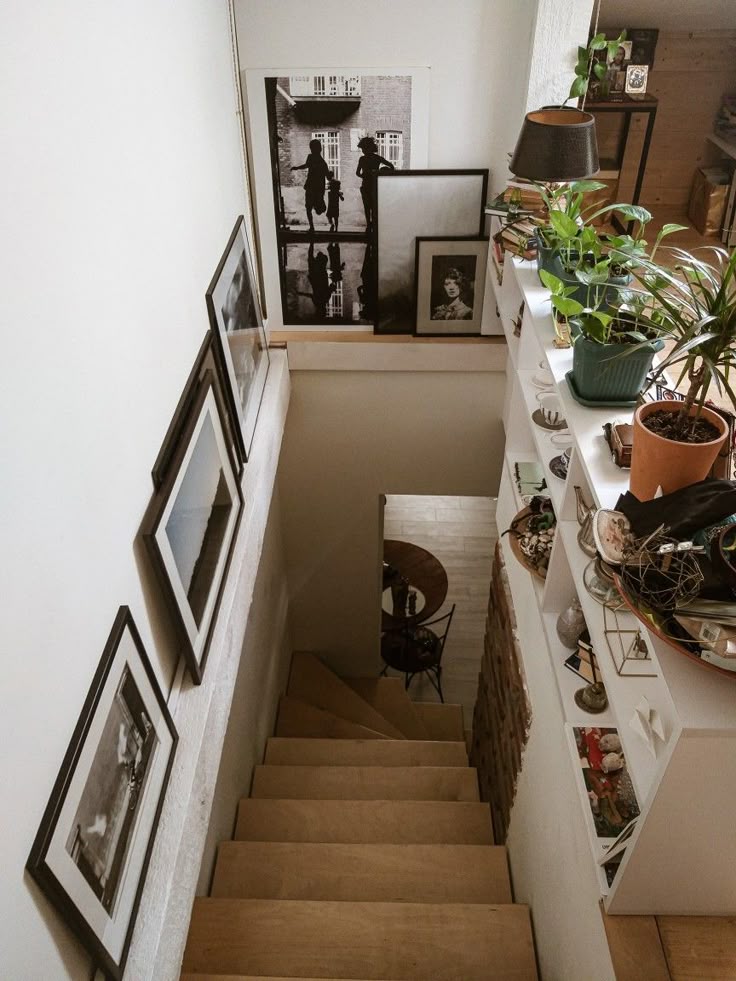 A staircase landing featuring a built-in white bookcase styled with plants and decor, paired with large-scale framed black-and-white photography on the adjacent wall.