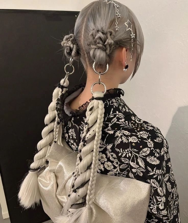 Woman from behind in a floral jacket, showing two complex, braided space buns in grey hair, connected by silver chains and star-shaped barrettes, for a goth prom hair up do.