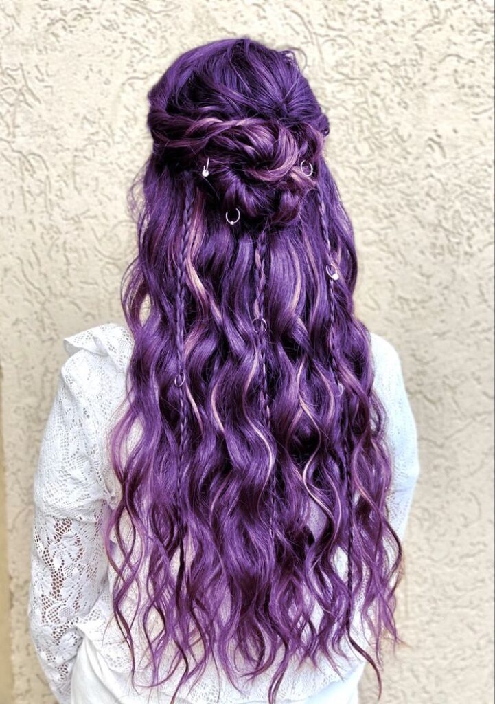 The back view of a whimsigoth prom hairstyle featuring long purple curls, small braids, and silver hair ring accessories.