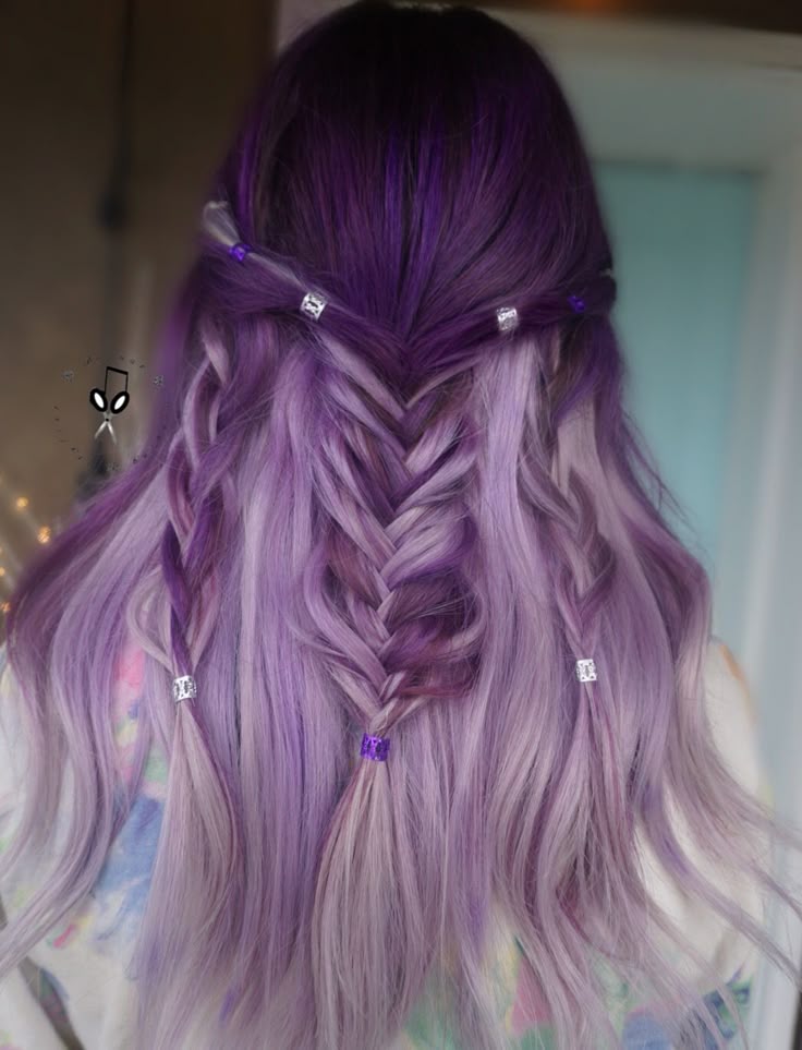 Woman from behind with two-toned purple and lavender hair in a half-up, half-down style featuring a central fishtail braid and small, metal-beaded braids, exemplifying a whimsigoth prom hair look