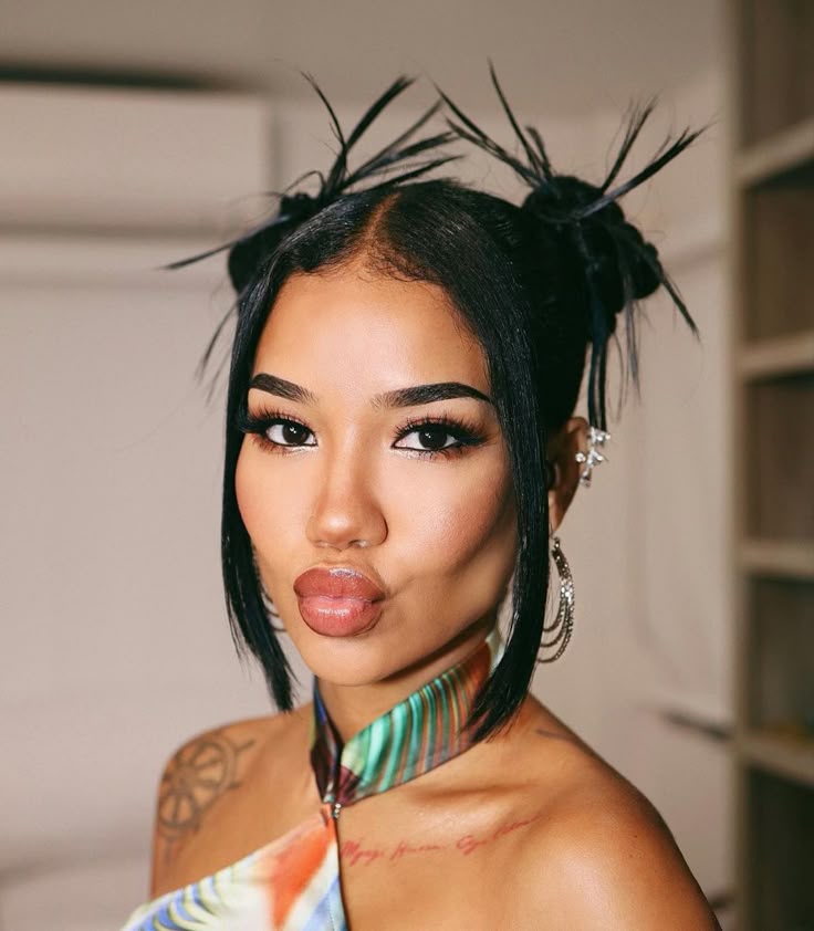 Frontal view of a woman with dark hair in two spiky space buns with sleek face-framing strands, showcasing a Y2K prom hair style.