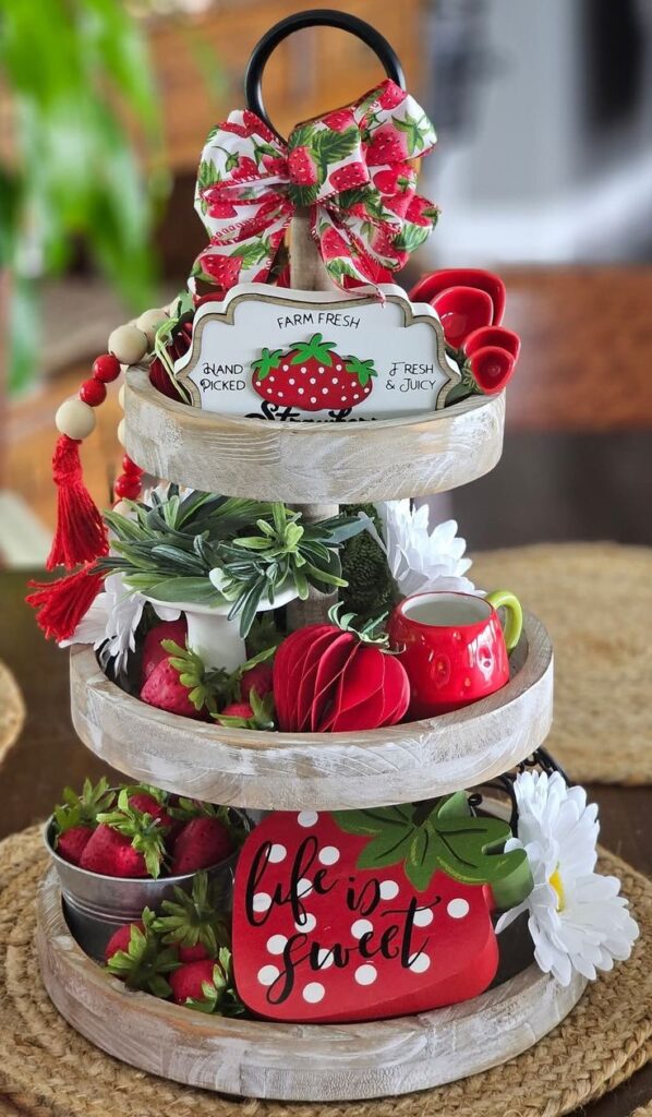 A rustic three-tiered wooden tray filled with farmhouse strawberry decor and white daisies.