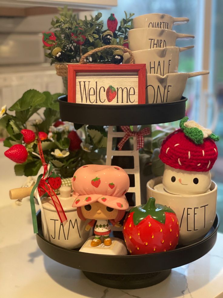 A two-tiered black metal tray styled with Strawberry Shortcake figures, a ceramic strawberry, and white "Jam" and "Sweet" canisters.