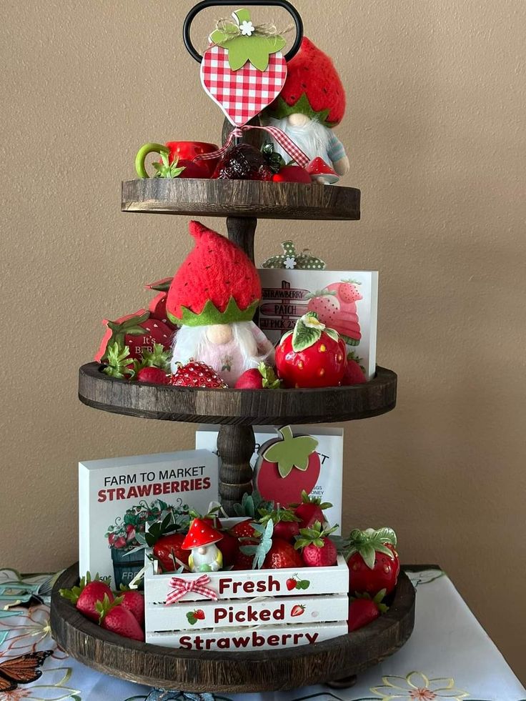 A three-tier dark wood tray decorated with strawberry-themed gnomes, a "Fresh Picked Strawberry" wooden crate, and various berry-shaped ornaments.