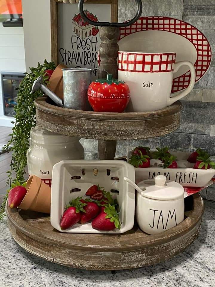 A dark wood tiered tray featuring farmhouse kitchen strawberry decor and ceramic jars.