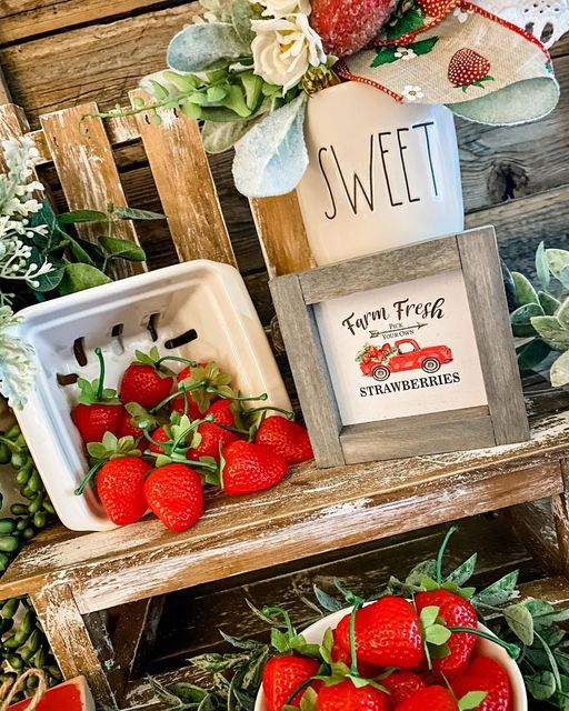 A wooden farmhouse shelf featuring a framed strawberry sign and red strawberry decor.