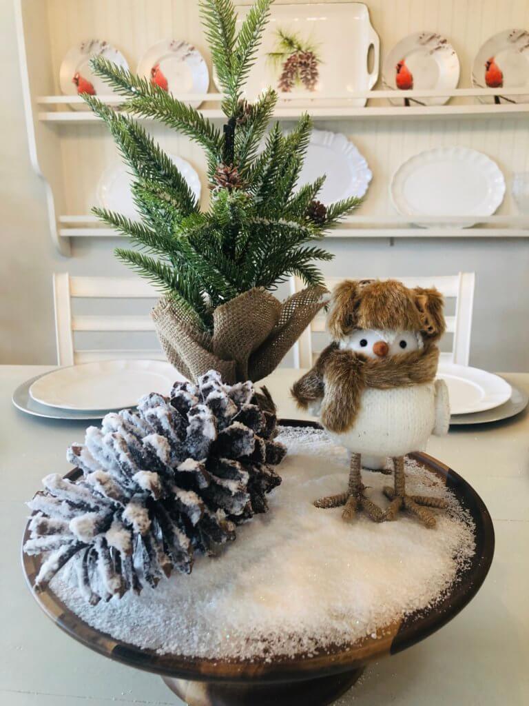 Snowy tablescape winter decor idea with pinecone and knit owl figurine