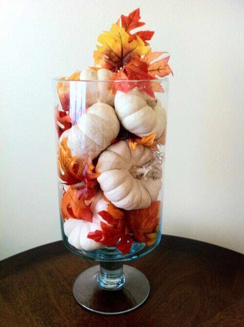 Easy fall decor idea using a glass vase filled with mini pumpkins and leaves