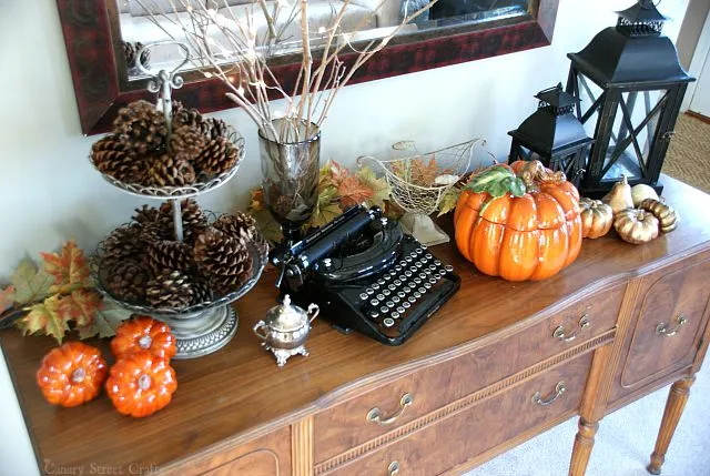 Vintage sideboard fall home decor idea with pinecones, lanterns, and ceramic pumpkin
