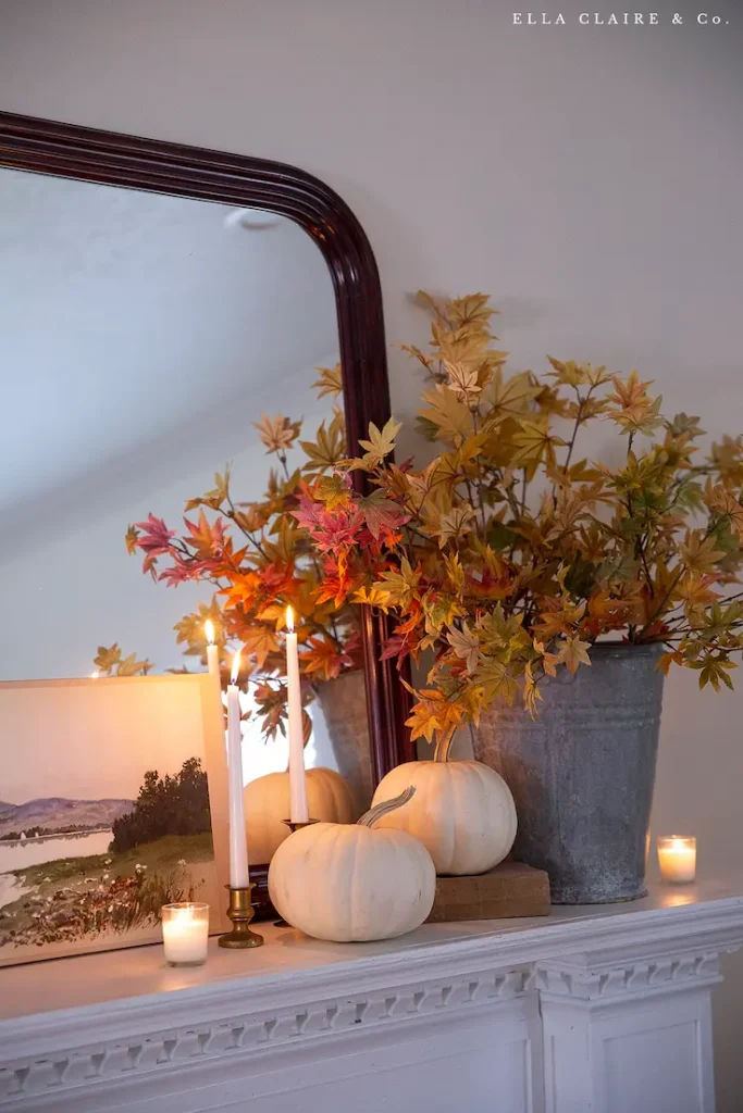 Elegant fall mantel decor idea with white pumpkins, fall branches, and candlelight