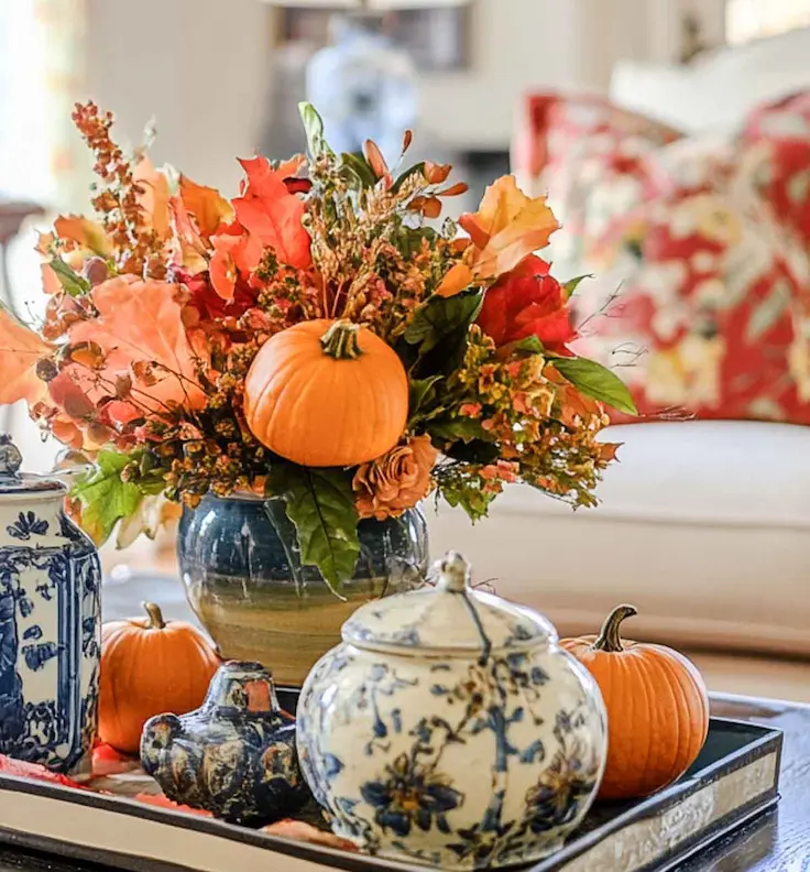 Fall coffee table styling idea with blue and white pottery and pumpkin floral arrangement