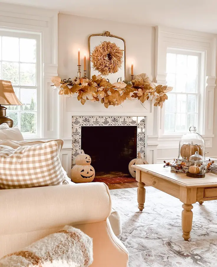 Neutral fall mantel decor idea with feather wreath, leaf garland, and taper candles