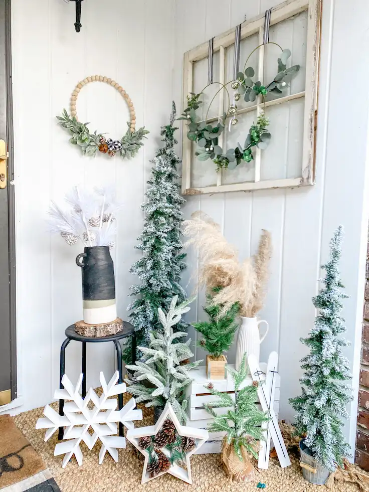 Layered porch corner winter styling idea with flocked trees and pampas grass