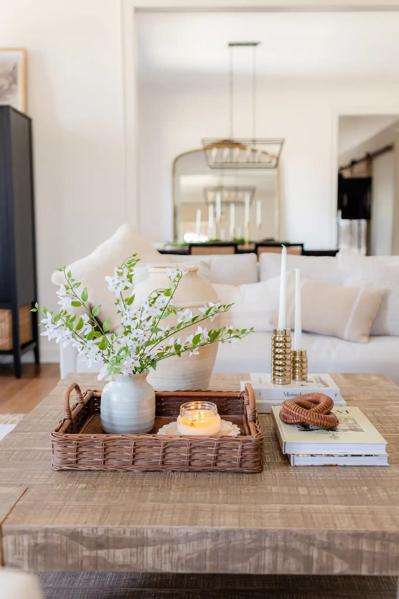 rectangle walnut coffee table decor with a potted plant in a woven basket, decorative plate and stacked books in a living room with a leather sofa