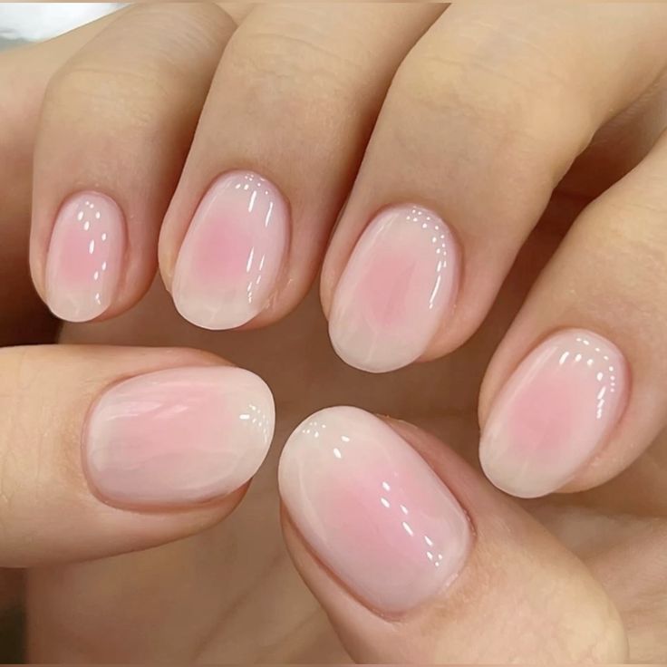 Short soft pink nails with a blush gradient, short milky pink nails with a jelly finish, short light pink nails with an ombre effect, short oval nails, blush nails, aura nails, pink gradient manicure, glossy pink nails, soft pink ombre, gel nails